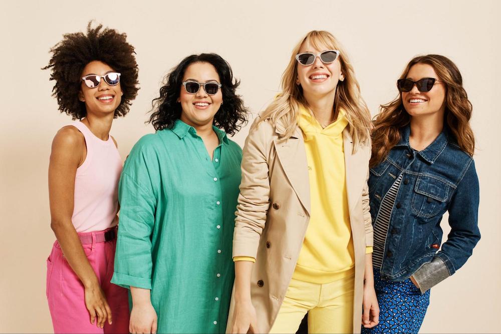 Four smiling young women wearing bright colors and polarized sunglasses.